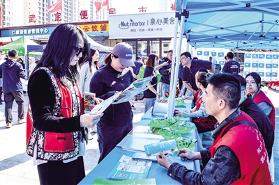 活动现场，居民围在招聘展板前仔细查看岗位信息。韩堃摄