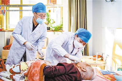 图为医生将调整好的义齿为老人装上。韩堃摄