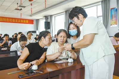 图为参训学员专注练习钩针编织技艺，授课老师手把手教学。于宏摄